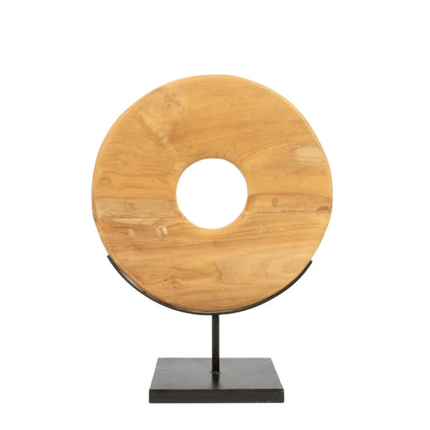 A round, teakwood sculpture with a central hole, resembling a wooden donut, is mounted on a black metal stand with a rectangular base. This decorative item adds an elegant touch to any home interior.