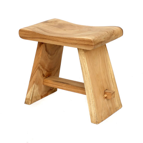 This Suar Wood stool boasts a natural finish, featuring a rectangular seat and two angled legs connected by a horizontal support bar. The design is minimalist and embraces a rustic, natural style.