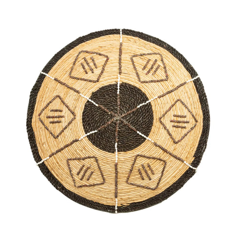 A round woven basket, perfect for an ethnic wall display, features a central black circle surrounded by alternating black and tan sections. Each section showcases angular diamond patterns and diagonal lines, adding a natural vibe to its symmetrical design.