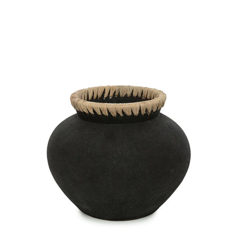 A round, textured black terracotta vase with a wide mouth featuring a braided natural fiber rim exudes coastal vibes. The vase has a smooth, matte finish and sits against a plain white background.