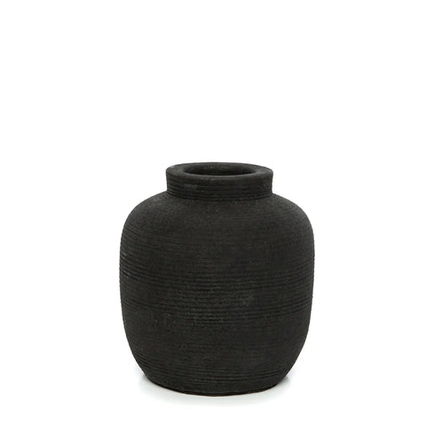 A dark, ribbed texture ceramic vase with a simple, rounded shape and narrow opening stands gracefully against a plain white background.