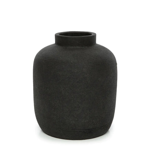 A black, textured ceramic vase with a ribbed texture features a round body and narrow opening, set against a white background. The vase has a simple, minimalist design, perfect for displaying dried flowers.