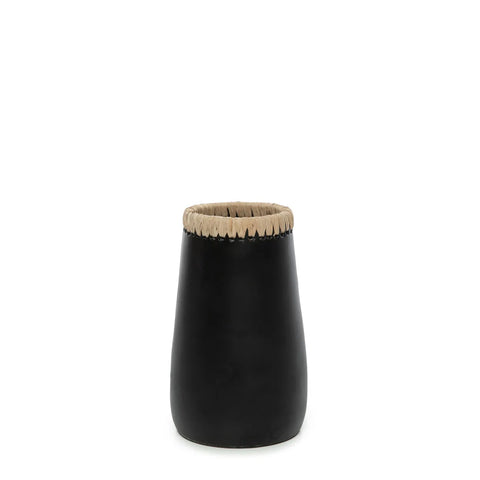 A black, cylindrical object with a beige, raffia-detailed rim sits against a white background.