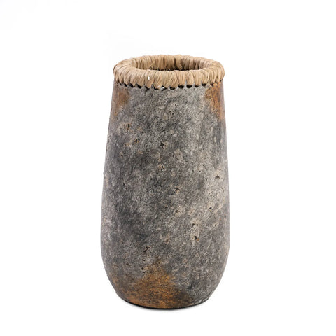 A tall, textured Antique Grey stone vase with a slightly tapered shape and a rim wrapped in woven straw or rope material offers an elegant touch to any room.