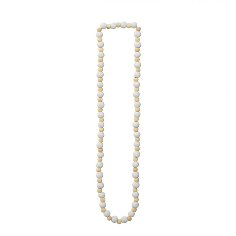 A long necklace, designed for a natural look, features round, alternating white and beige beads. Perfectly arranged in a loop on a plain white background, it adds an elegant touch to interior decorating.