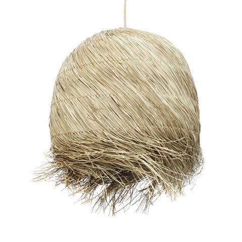 A handwoven grass pendant lamp crafted from natural dried grass fibers, featuring a dome shape with a rough, textured surface. The strands create an uneven fringe, giving a rustic, handmade appearance and adding a boho charm against the white background.