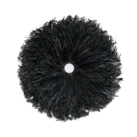 A black juju hat with densely packed feathers radiates from a central point, perfect for bohemian decor. Displayed against a white background, this striking piece adds an artistic touch to any home interior.