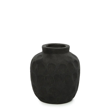 A textured black ceramic vase with a ribbed texture and narrow opening, set against a plain white background, exudes elegance. Perfect for showcasing dried flowers or complementing terracotta vases in any decor setting.