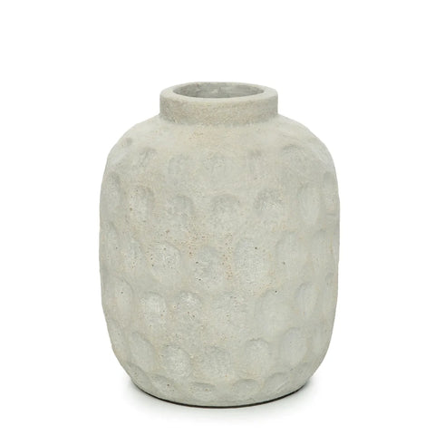 A textured, gray ceramic vase with a rounded body and small opening showcases a ribbed circular pattern. This rustic, handmade piece resembles terracotta vases and is set against a plain white background, perfect for displaying dried flowers.