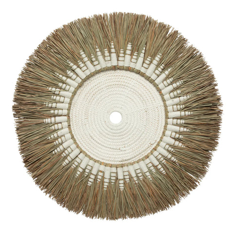 A bohemian coastal decorative wall hanging crafted from woven fibers and natural grass. This handcrafted wall art showcases a central white woven section surrounded by an outer ring of bundled, tan-colored grassy texture.