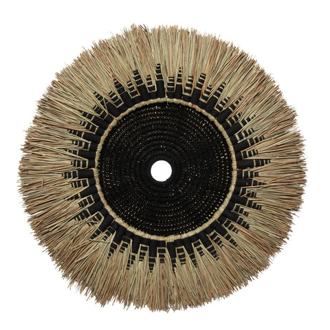 A circular, woven wall deco piece featuring a central black cotton macramé area surrounded by radiating natural fibers. The bohemian coastal design resembles a sunburst pattern, with alternating sections creating an intricate, textured look.