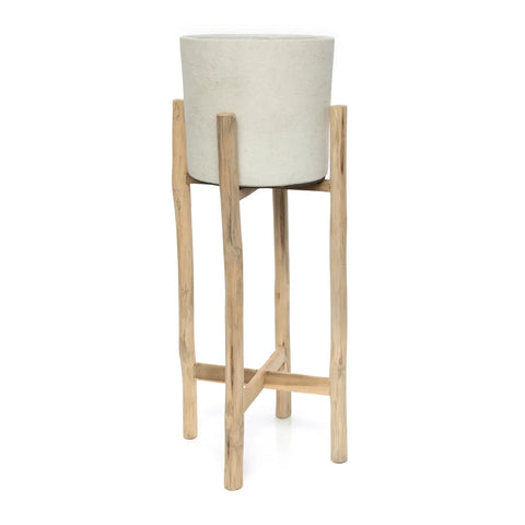 A terracotta cylindrical planter is elegantly positioned on a tall, natural wood stand crafted from teak branches with four legs connected by crossbars, creating a stunning piece of interior decor against a plain white background.