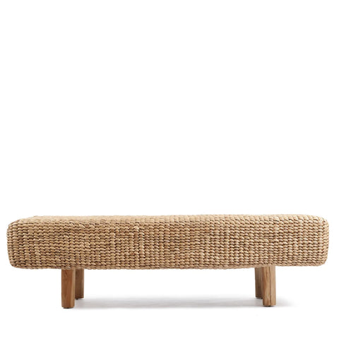 A Water Hyacinth Bench with a rectangular shape rests on four short wooden legs, showcasing its simple and rustic design. Crafted from eco-friendly fibers, this sustainable seating option adds an earthy touch to any space.