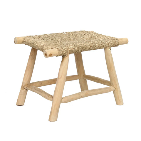 A small, square wooden stool with a woven seagrass seat exudes a boho style charm. The stool's four slightly angled legs lend it a rustic appearance, and the teak wood boasts a light, natural finish that enhances its simple and traditional design.