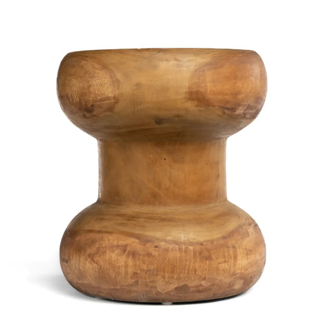 The Wayra stool is a wooden, round piece with a symmetrical design featuring a wider base and top, connected by a narrower middle section. Crafted from suar wood, it boasts a smooth finish that highlights its natural grain and organic shape.