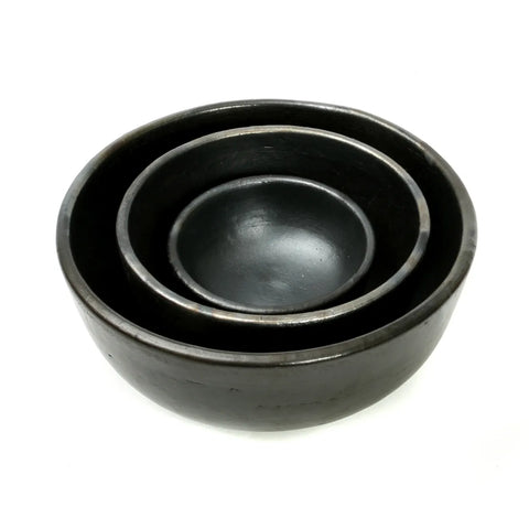 Three nested black ceramic bowls of varying sizes are placed inside one another against a plain white background, showcasing a unique tableware design with an antique look.