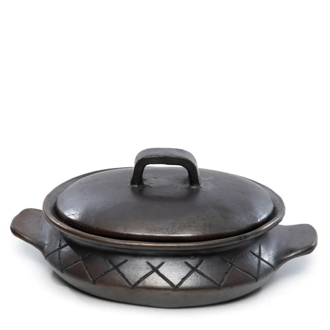 A dark, round ceramic pot with a matching lid and two side handles showcases a unique design. The crisscross pattern around its body adds to its rustic charm. It’s perfectly placed against a plain white background.