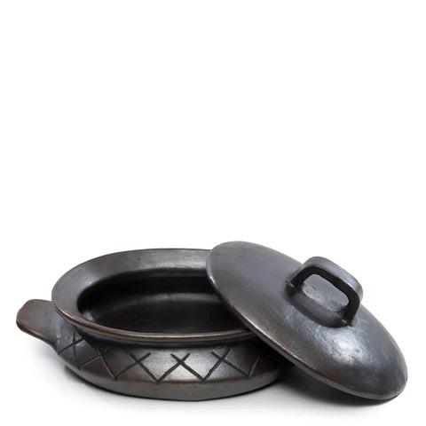 A black clay pot with a handle and decorative diamond pattern around the side, featuring a unique design. It comes with a matching lid placed off-center to the right, giving the set a rustic, handcrafted appearance reminiscent of traditional terracotta tableware.