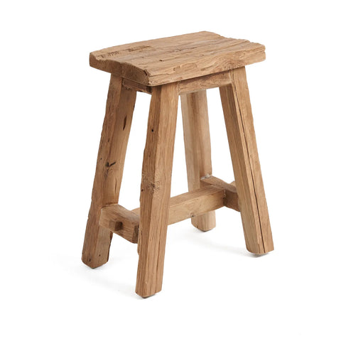 A rustic Shoji stool crafted from reclaimed teak wood features a rectangular seat and four sturdy, angled legs. The wood boasts a natural, unfinished look with visible grain and texture, embodying the charm of rustic design.