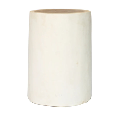 A simple, cylindrical, off-white ceramic stool with a smooth surface and a slightly rounded top embodies natural and organic design.