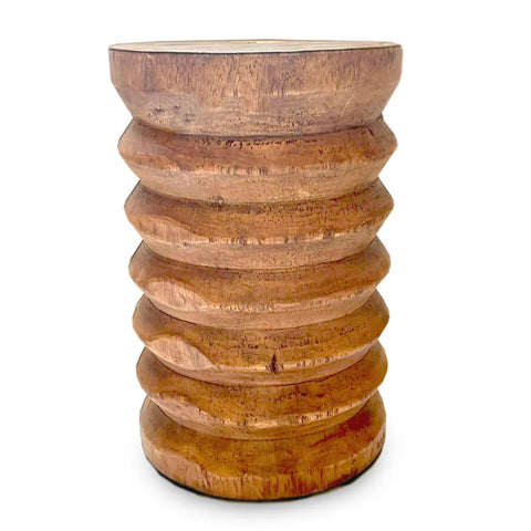 A decorative wooden stool handcrafted from suar wood with a textured, ribbed design. The polished surface highlights the natural grain and warm brown tones, making it perfect as a side table. Its cylindrical shape features a slightly wider base and top.