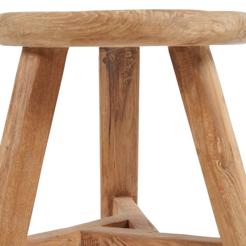 Close-up of a Noguchi stool made from reclaimed teak wood, featuring a round seat and angled legs. The natural wood grain and texture are visible, giving it a rustic appearance. The legs are connected by a supportive crossbar at the base, making it an elegant versatile side table.