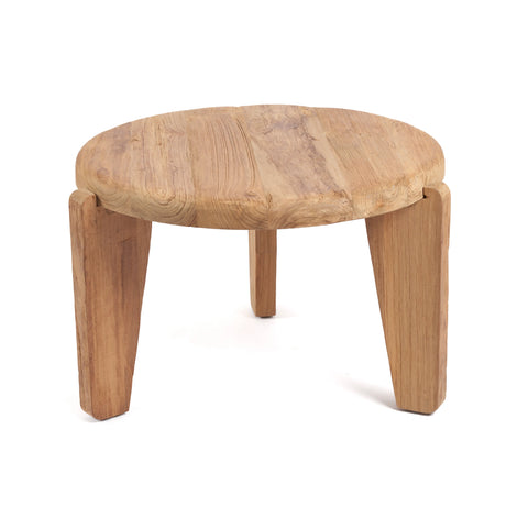 A small, round wooden stool with a rustic design, crafted from reclaimed teak wood. It features a thick, smooth seat and three sturdy, angled legs. The stool's simple and natural appearance adds an eco-friendly warmth to the setting.