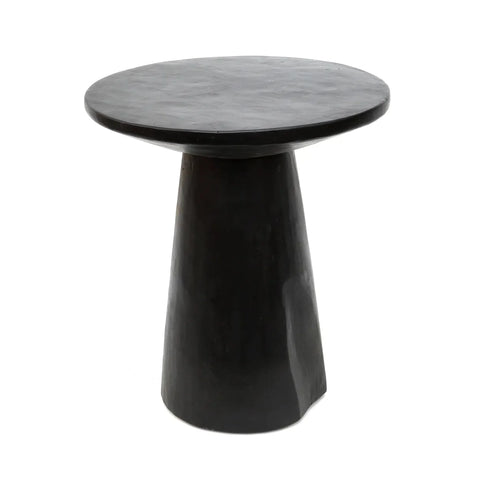 A small, round, black side table crafted from Munggur wood features a conical base and a smooth, minimalist design.