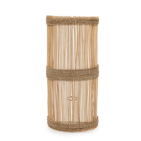 A tall, cylindrical wicker basket with vertical bamboo slats and two horizontal rope bands for support stands upright on a plain, white background, evoking the breezy aesthetic of coastal decor.