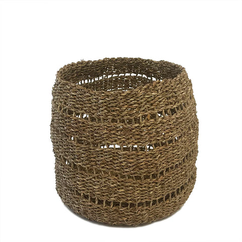 A round, seagrass woven basket made of natural fibers with an intricate pattern. It has an open top and is light brown, showcasing a textured surface. Ideal for towel storage, the basket sits on a white background.