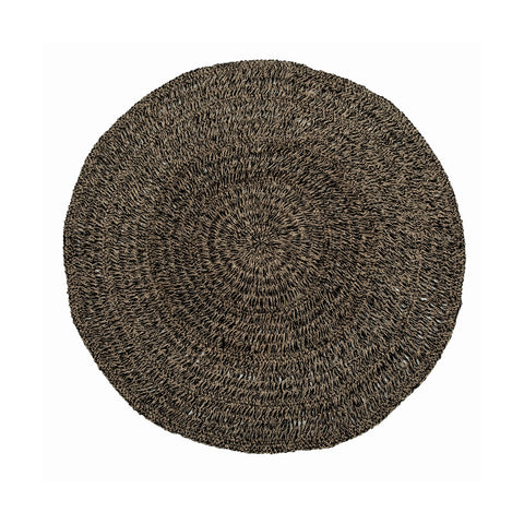 A round, woven seagrass mat with a textured pattern showcases natural brown tones and a rustic appearance. Its slightly uneven surface enhances the organic look, while its hardwearing quality ensures lasting durability.