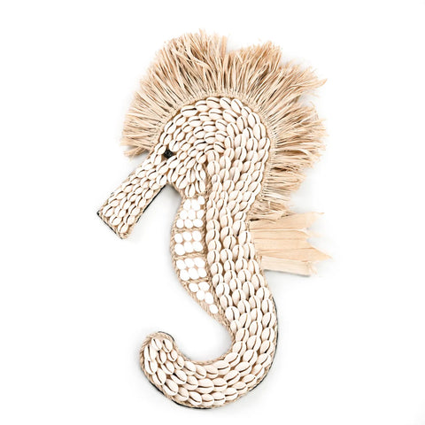 A decorative sea horse crafted from white shells features a textured beige material forming mane-like raffia fringes along its head and back. The design is elegantly set against a plain white background.