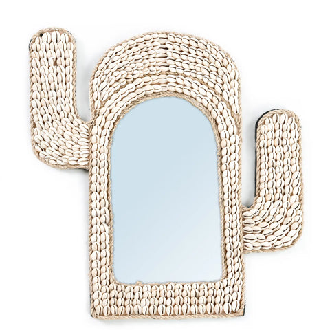 A cactus-shaped mirror with a frame adorned in cowrie shells, featuring two upward-facing arms and a blue reflective surface at its center. This unique piece is an ideal gift for those who appreciate coastal decor.