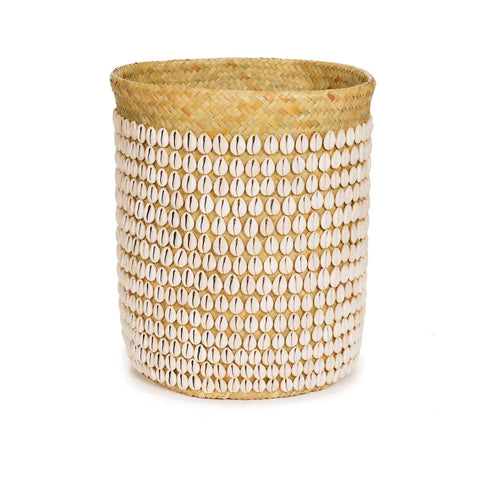 A handmade cylindrical pandan basket, adorned with rows of white Balinese cowrie shells, set against a plain white background. The basket features a natural straw color and texture, with the shells providing a decorative contrast.