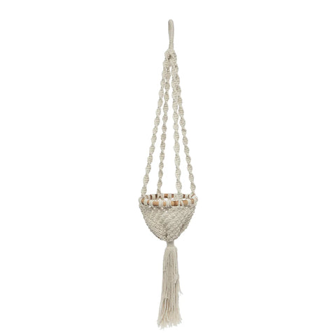 A beige macramé plant holder with intricate knots and patterns, hanging gracefully from a loop. It features a round basket and a long tassel at the bottom, perfect for displaying hanging plants.