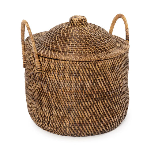 A brown, round wicker basket with a snug-fitting lid and two handles on either side exudes the rustic beauty of rattan. Its diagonal weave pattern offers a textured appearance, while maintaining a high-end look that complements any decor.