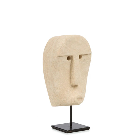 A minimalist stone sculpture of an abstract face with simple features, expertly hand-carved from sandstone, mounted on a black metal stand against a plain white background.