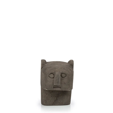 Part of the Sumba Stone collection, this hand-carved sculpture is crafted from dark gray stone, featuring a stylized humanoid face with a prominent nose and rounded ears. It stands gracefully on a rectangular base against a plain white background.