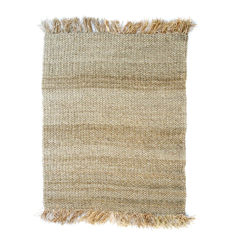 A rectangular woven jute rug with fringe on the shorter edges, this hardwearing piece showcases natural fibers for a textured, earthy look. The rustic fringe adds charm to the fringed carpet, perfectly displayed against a white background.