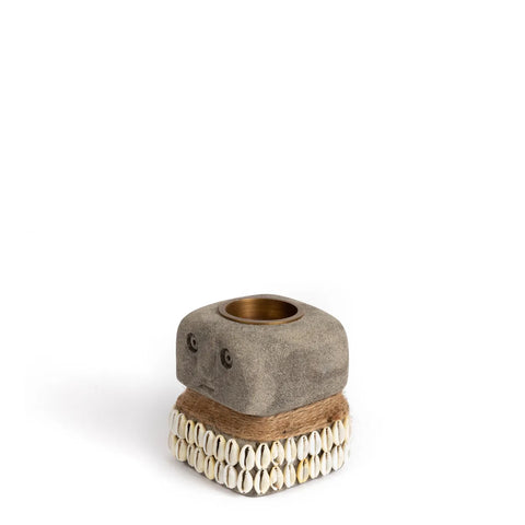 This hand-carved decorative candle holder features a square Sumba Stone top with a round opening perfect for tealight holders. Adorned with shells and twine wrapped around the base, it stands elegantly against a plain white background.