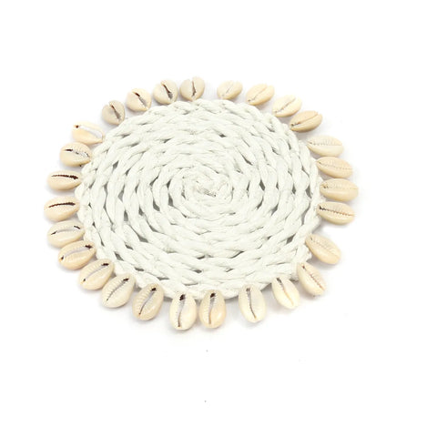 A round, woven white coaster featuring a border of light beige cowrie seashells, embodying an island style. The braided texture forms a spiral pattern at the center, while the shells are evenly spaced along the edge, enhancing its coastal charm.