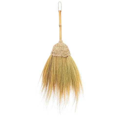 A handmade Indonesian broom featuring natural fibers and a wooden handle with woven binding. The long, natural-colored bristles fan out elegantly. The handle includes a loop at the top for hanging, set against a plain white background.