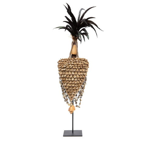 This Bali art-inspired decorative sculpture features a tall, elongated form with black feather-like elements at the top. The central body is adorned with numerous shell-like textures, tapering down to a point, all mounted on a slender black stand, making it a unique handmade centerpiece.