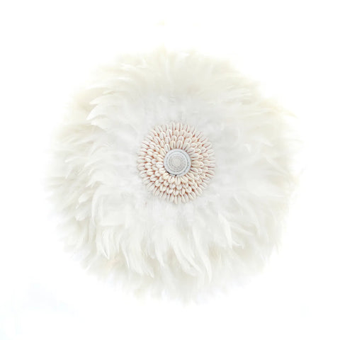 A round, fluffy white feather wall display with a central pattern of hand-placed shells resembling a flower. The soft texture exudes bohemian decor vibes, with feathers radiating outward in a delicate circular arrangement.