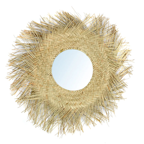 A round rattan wall mirror encased in a circular woven frame with a sunburst design featuring straw-like, textured edges. The intricate weaving pattern radiates a natural color and adds a boho touch to any space, creating an effortlessly rustic aesthetic.