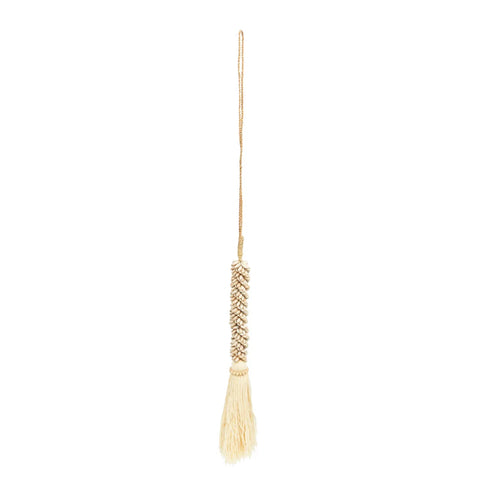 A handmade tassel, featuring an intricate knotted design along the cord and a cluster of fringe at the end, hangs vertically against a plain white background. Its bohemian decor style adds a touch of elegance and charm to any space.