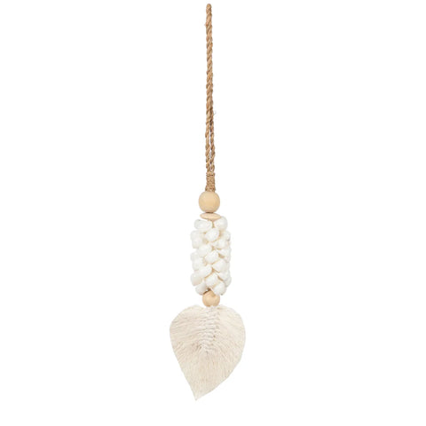 This decorative hanging piece, handmade by Balinese craftsmen, features a cluster of white shells and wooden beads with a leaf-shaped tassel at the bottom, all suspended from a brown rope, perfectly capturing a bohemian atmosphere.