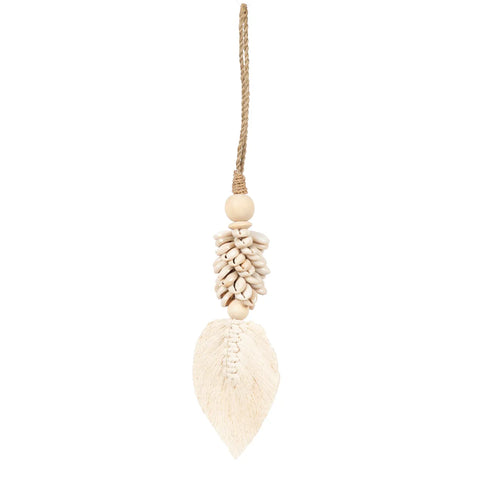 A handmade decorative hanging ornament featuring a cluster of small white shells above a cream-colored, leaf-shaped tassel. This piece exudes a bohemian atmosphere and is suspended by a thin, light brown string.