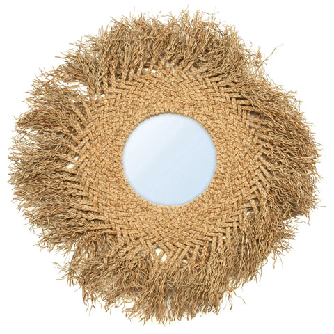 Round rattan mirror with a frame made of woven and frayed natural fibers, resembling a sunburst pattern. The center features a reflective surface, surrounded by intricate braided details and outward-reaching strands that exude an earthy boho vibe and coastal texture.