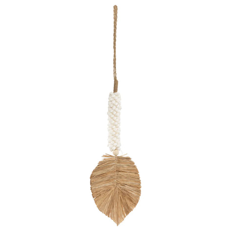 A decorative wall hanging featuring a brown leaf-shaped design made of natural fibers, crafted by Balinese craftsmen. It has a white beaded handle for hanging, with tassels that enhance its bohemian atmosphere.